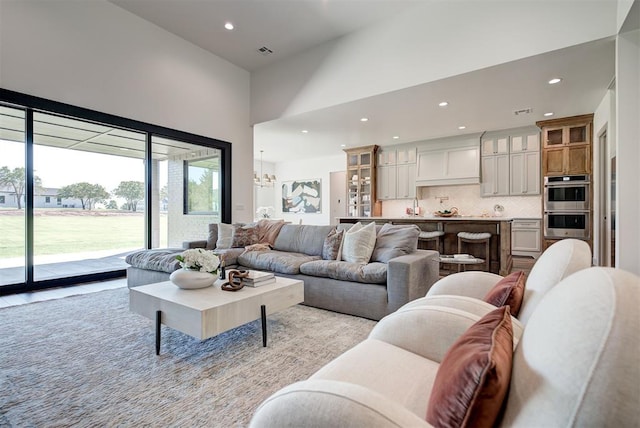 living room with a towering ceiling, an inviting chandelier, and sink