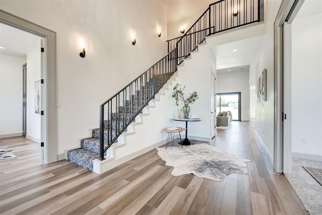 staircase featuring hardwood / wood-style floors and a towering ceiling