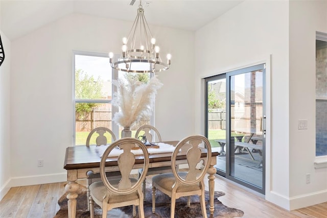 dining room with vaulted ceiling, an inviting chandelier, and light hardwood / wood-style flooring