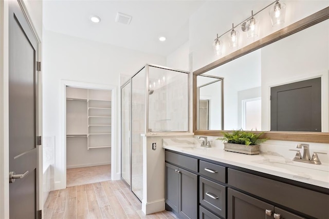 bathroom with vanity, a shower with shower door, and hardwood / wood-style flooring