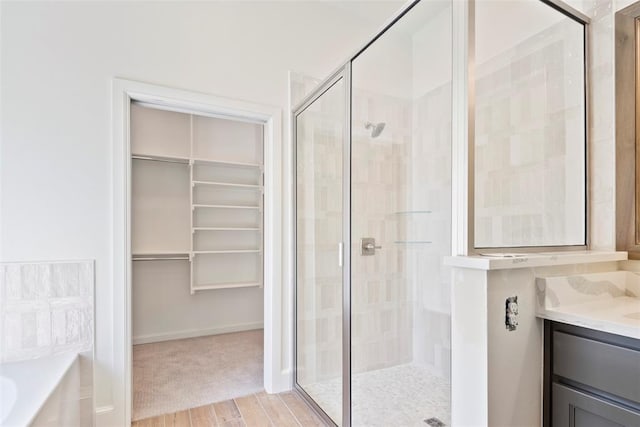 bathroom featuring vanity, wood-type flooring, and plus walk in shower