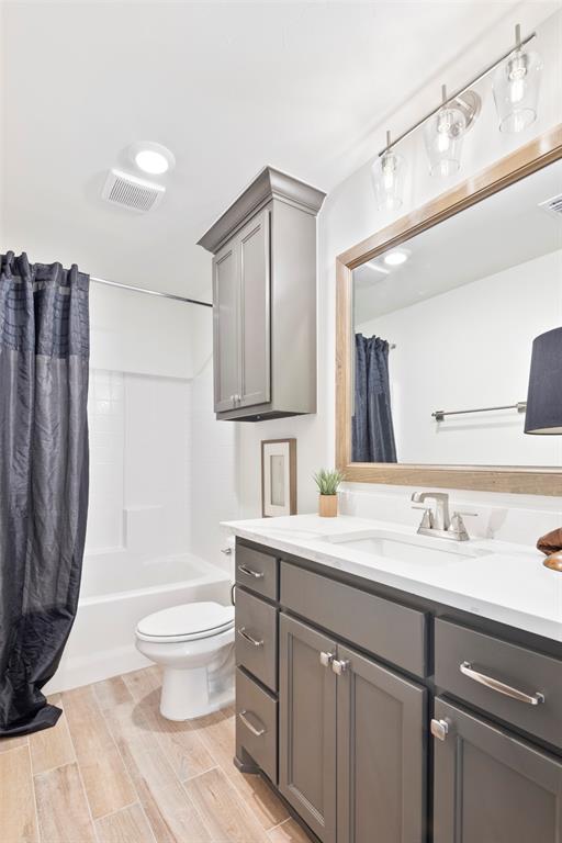 full bathroom with vanity, toilet, wood-type flooring, and shower / tub combo with curtain