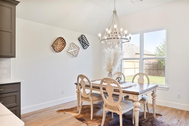 dining room with light wood-type flooring and an inviting chandelier