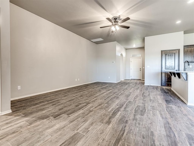 unfurnished living room with hardwood / wood-style flooring and ceiling fan