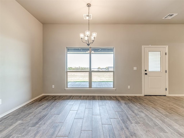 unfurnished room featuring a notable chandelier and hardwood / wood-style flooring