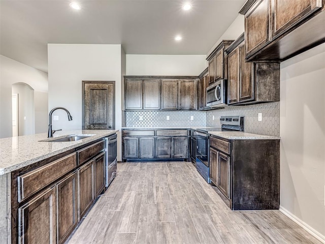 kitchen with sink, dark brown cabinetry, stainless steel appliances, and light hardwood / wood-style flooring