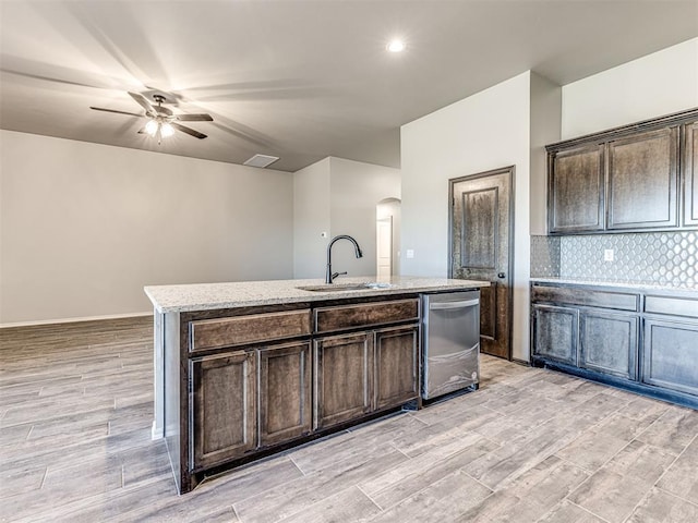 kitchen with dark brown cabinets, a kitchen island with sink, sink, dishwasher, and light hardwood / wood-style floors