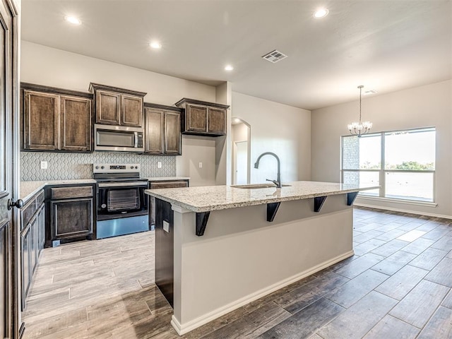 kitchen featuring stainless steel appliances, light hardwood / wood-style flooring, and an island with sink