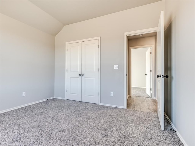 unfurnished bedroom with lofted ceiling, light carpet, and a closet