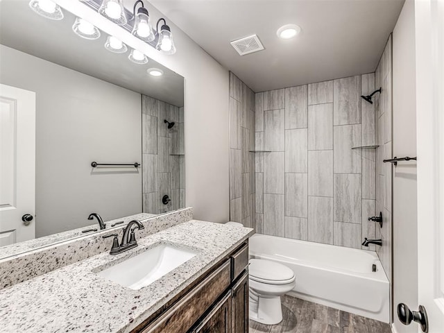 full bathroom with vanity, hardwood / wood-style flooring, toilet, and tiled shower / bath combo