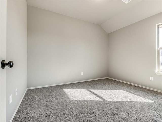 carpeted spare room featuring vaulted ceiling