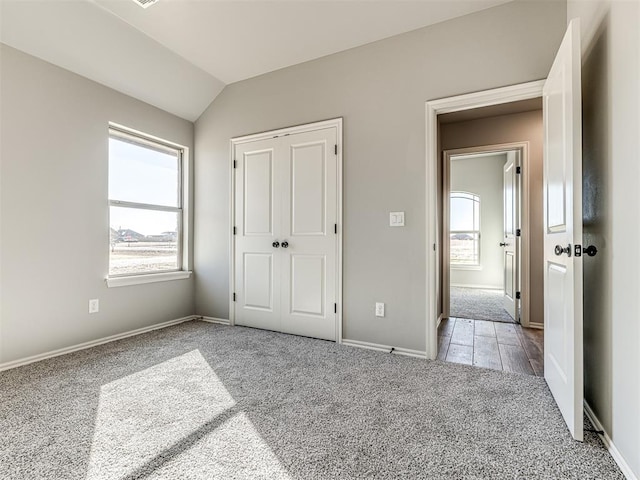 unfurnished bedroom with light carpet, a closet, and lofted ceiling