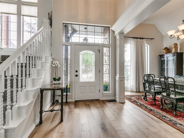 entryway featuring high vaulted ceiling, an inviting chandelier, and light hardwood / wood-style flooring