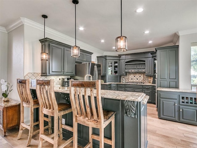 kitchen featuring gray cabinetry, light hardwood / wood-style floors, stainless steel refrigerator with ice dispenser, and hanging light fixtures