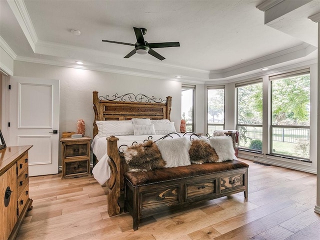 bedroom with a raised ceiling, ceiling fan, ornamental molding, and light wood-type flooring