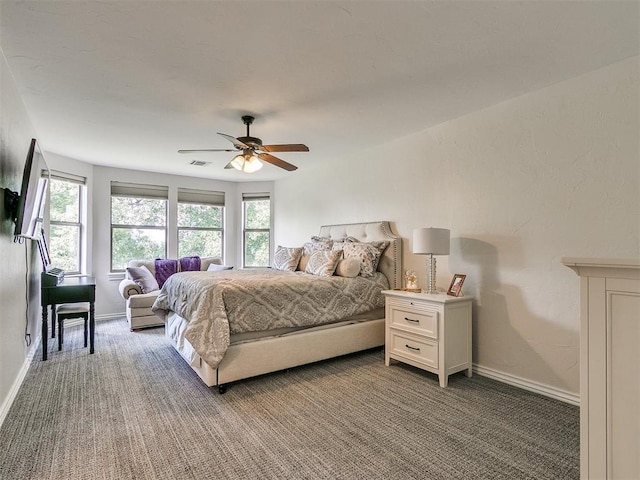 bedroom featuring multiple windows, ceiling fan, and dark colored carpet