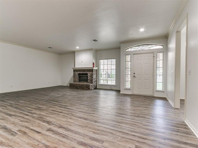 foyer featuring a brick fireplace, crown molding, and light wood-type flooring