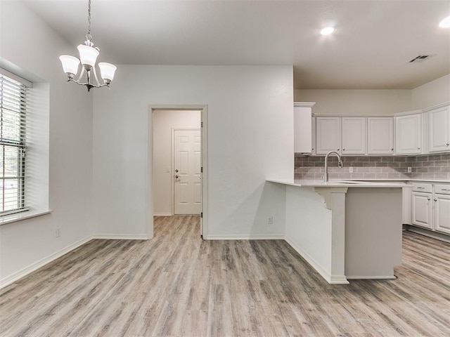 kitchen featuring white cabinetry, tasteful backsplash, a kitchen breakfast bar, light hardwood / wood-style floors, and decorative light fixtures