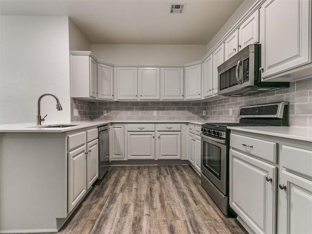 kitchen featuring appliances with stainless steel finishes, dark hardwood / wood-style flooring, white cabinetry, and sink