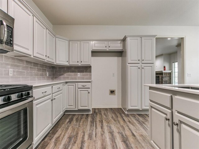 kitchen featuring backsplash, white cabinetry, stainless steel appliances, and dark hardwood / wood-style floors