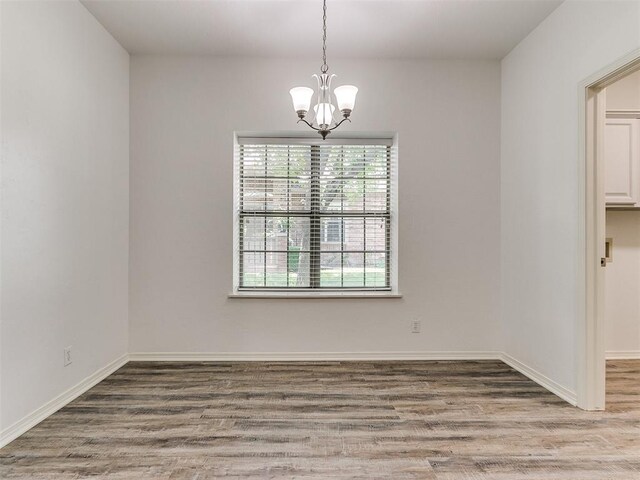 unfurnished room with wood-type flooring and an inviting chandelier