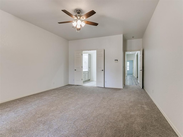 unfurnished bedroom featuring light colored carpet, ensuite bath, and ceiling fan