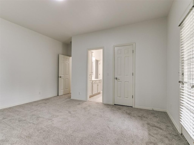 unfurnished bedroom featuring light colored carpet and ensuite bath