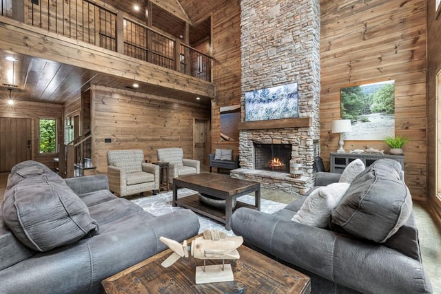 living room featuring a fireplace, a towering ceiling, wood ceiling, and wood walls