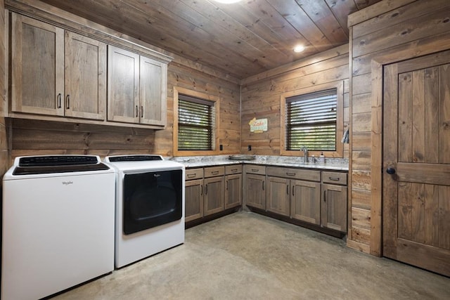 clothes washing area with washing machine and clothes dryer, wood walls, cabinets, and a healthy amount of sunlight