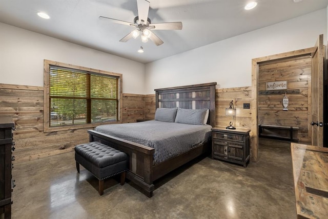 bedroom with ceiling fan and wood walls