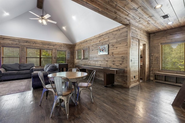 dining room featuring high vaulted ceiling, dark hardwood / wood-style floors, ceiling fan, and wooden walls