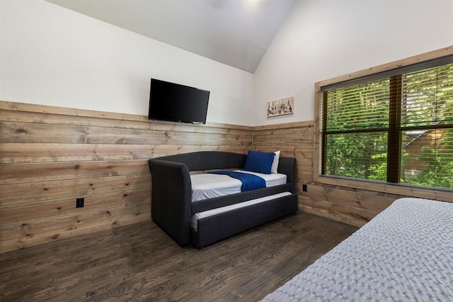 bedroom with wooden walls, high vaulted ceiling, and dark hardwood / wood-style floors