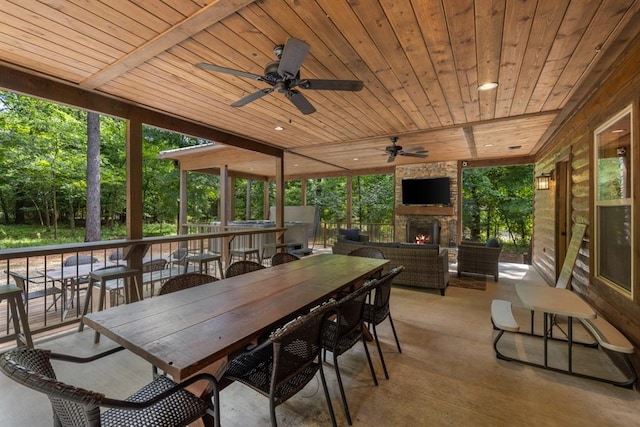 sunroom / solarium with an outdoor stone fireplace, ceiling fan, and wood ceiling