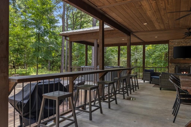 sunroom / solarium featuring an outdoor stone fireplace, lofted ceiling with beams, and wood ceiling