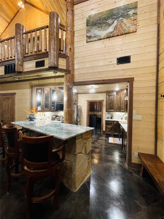 interior space featuring wood walls, high vaulted ceiling, hanging light fixtures, light stone countertops, and wood ceiling