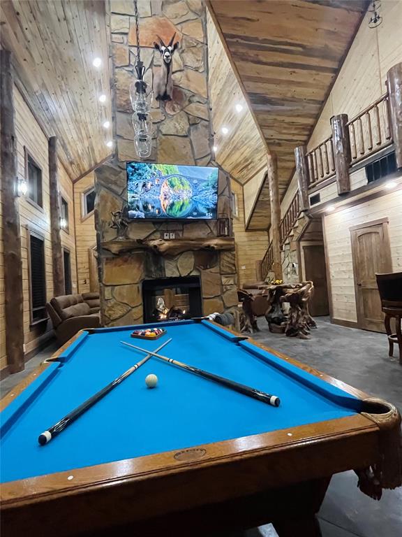 recreation room featuring wood ceiling, wooden walls, high vaulted ceiling, billiards, and a fireplace