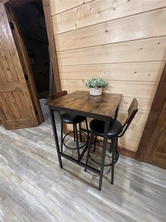 dining area with light hardwood / wood-style flooring and wooden walls