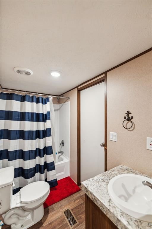 full bathroom with wood-type flooring, vanity, shower / tub combo, and toilet