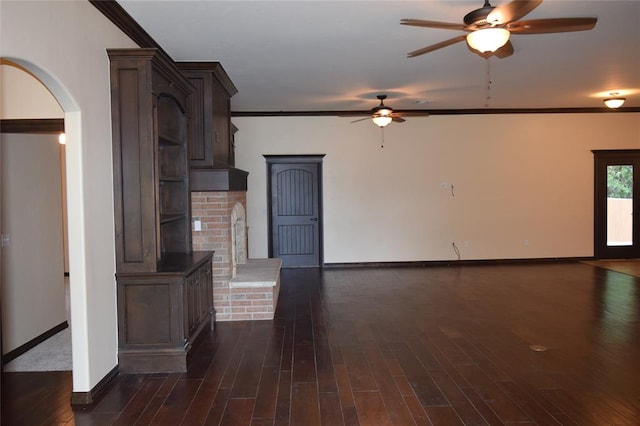 unfurnished living room with ceiling fan, ornamental molding, and dark wood-type flooring