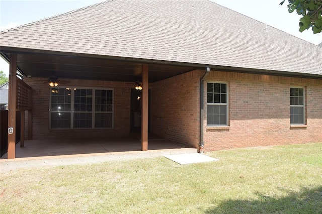 rear view of property featuring ceiling fan and a lawn