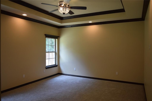 carpeted spare room with a raised ceiling, ceiling fan, and crown molding