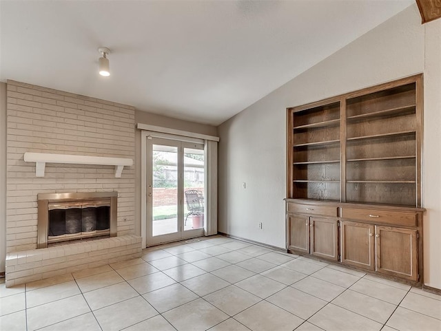 unfurnished living room with a fireplace, light tile patterned floors, and vaulted ceiling