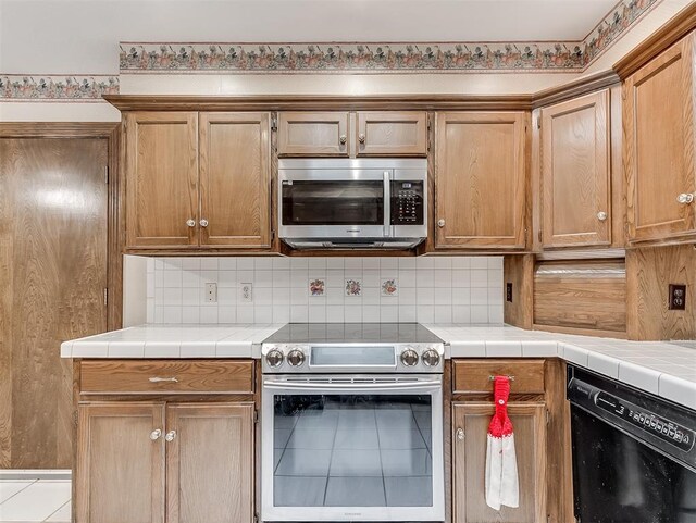 kitchen featuring tile countertops, backsplash, and appliances with stainless steel finishes