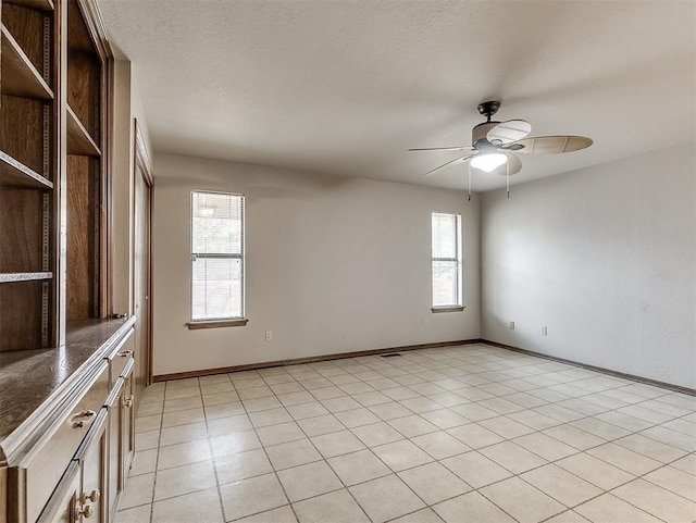 unfurnished room with ceiling fan and light tile patterned flooring