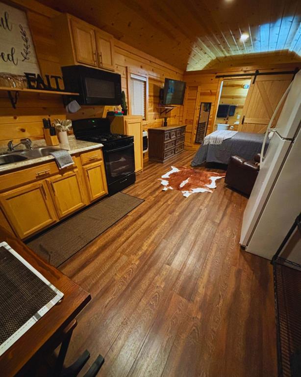 988 Ridge Point Rd, Fort Towson, OK 74735 - kitchen with black appliances, wood walls, light wood-style floors, light countertops, and wood ceiling