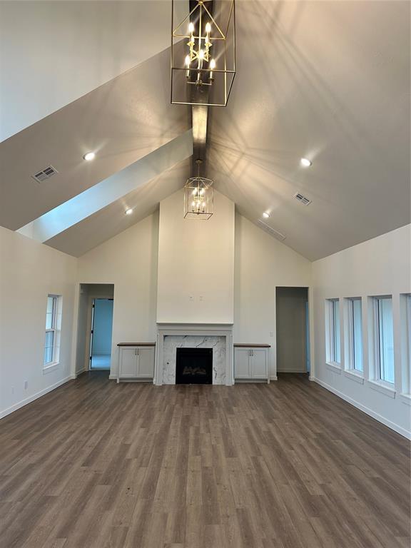 unfurnished living room featuring wood-type flooring, a fireplace, high vaulted ceiling, and a notable chandelier