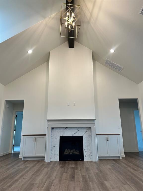 unfurnished living room featuring wood-type flooring, high vaulted ceiling, an inviting chandelier, and a high end fireplace