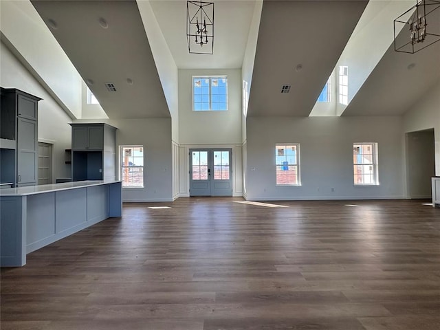 unfurnished living room featuring dark hardwood / wood-style flooring, plenty of natural light, french doors, and an inviting chandelier