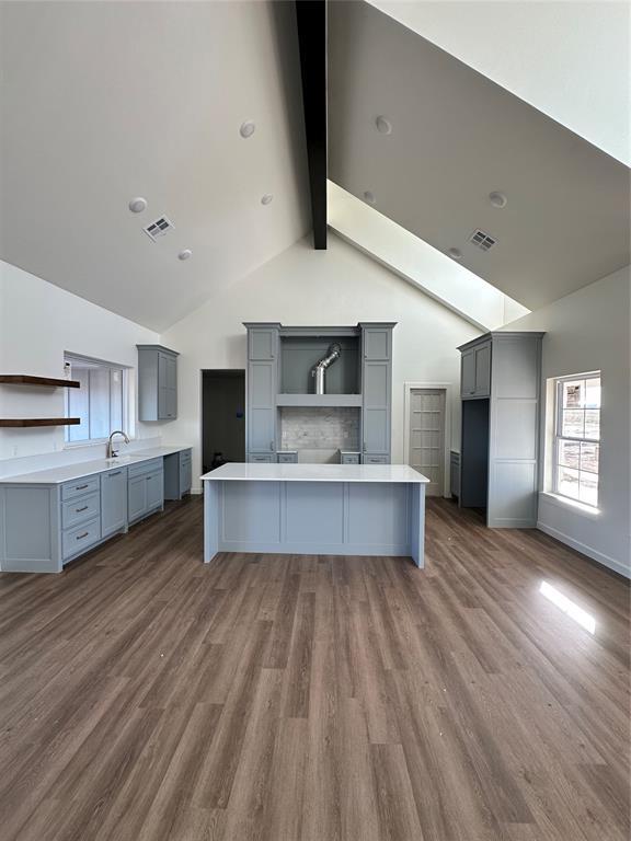 kitchen featuring a breakfast bar, beamed ceiling, sink, gray cabinetry, and dark hardwood / wood-style flooring