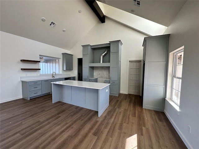 kitchen featuring gray cabinets, a kitchen island, dark hardwood / wood-style flooring, and beamed ceiling